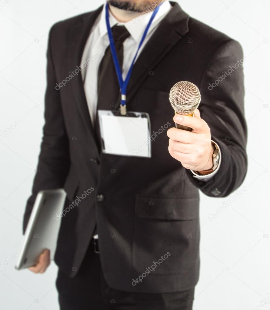 Hipster man in a classic suit isolated on a white background with a notebookt and microphone.