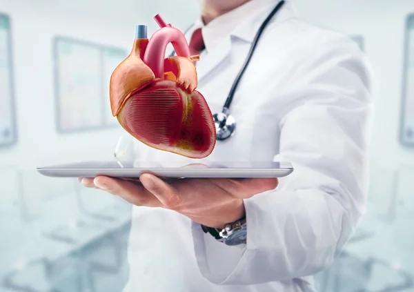 Doctor con estetoscopio en un hospital. Corazón en el comprimido —  Fotos de Stock