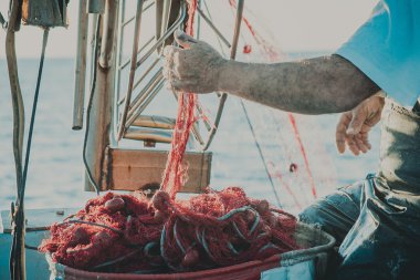Parlak turuncu Balık ağı ile yüzer. Fisher tekne bir denizde. Eski bir balıkçı elinde