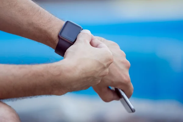 Männliche Hände mit schwarzer Smartwatch auf dem Hintergrund eines Wasserpools — Stockfoto