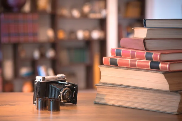 Pila de libros antiguos y cámara vieja sobre mesa de madera, imagen retro filtrada —  Fotos de Stock