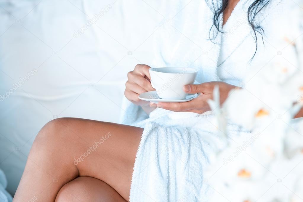 Young woman in a bathrobe with a cup of tea