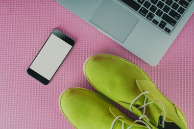 Dizüstü bilgisayar ve cep telefonu pembe bir arka plan üzerinde yeşil Erkek Ayakkabı
