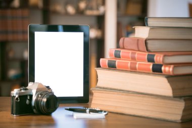 Eski kitaplar yığınla ve ahşap masa üzerinde retro filtre uygulanan görüntü tablet