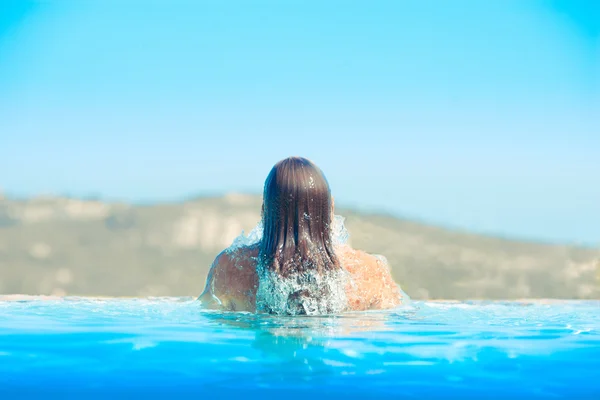 Menina bonita na piscina contra o pano de fundo de belas montanhas — Fotografia de Stock