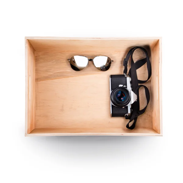 Vista superior de la caja de madera. Gafas de sol y cámara vieja dentro — Foto de Stock