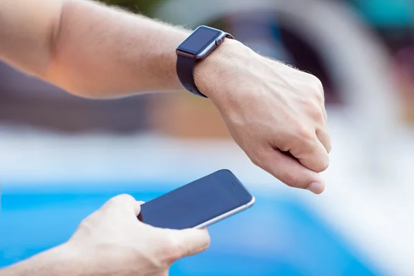 Mãos masculinas com smartwatch preto em um fundo de piscina de água — Fotografia de Stock