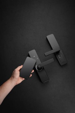 Bir insan şık ve modern bir kapı kolunu karanlık bir ortamda kilitlemek için akıllı bir anahtar kullanır. Tasarım, çağdaş evler için ideal güvenlik ve kolaylığı vurguluyor.