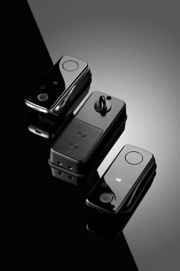 Üç modern kablosuz iletişim cihazı parlak siyah bir yüzeye yerleştirilmiştir. Cihazlar, gelişmiş teknolojiyi ön plana çıkaran, kolay kullanım düğmeleri olan minimalist bir tasarım içeriyor..