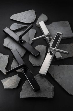 Biri siyah diğeri gümüş olmak üzere iki gösterişli kapı kulpu zarif bir şekilde dokuma levha taşından bir yatağa yerleştirilmiş, çağdaş tasarım ve zanaatkarlık sergilenmektedir..