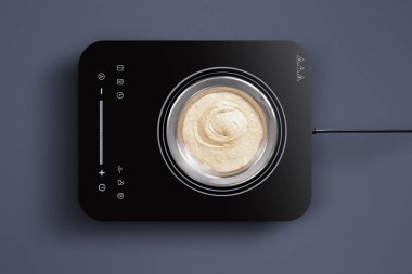 Çağdaş bir yemek makinesi karanlık bir yüzeyde, içinde pürüzsüz krema karışımını gösterir. Bu kurulum, modern mutfak teknolojisi ve gıda hazırlığını vurguluyor.