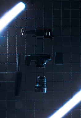 Karanlık bir ortamda birkaç silah bir şebeke duvarına monte edilir. Farklı silah türleri ve bir nesne düzgün bir şekilde sıralanır. Parlak ışıklar ekran etrafında.