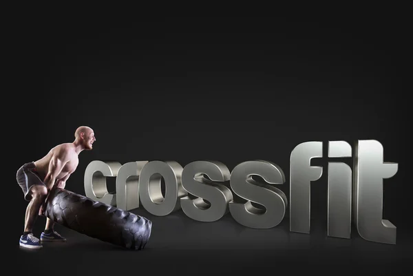 Un tânăr atletic ridică o anvelopă pe fundalul negru Expresii motivaționale de fitness — Fotografie, imagine de stoc