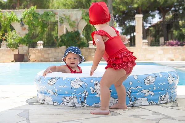 Un niño pequeño y feliz está jugando afuera en una piscina para bebés. — Foto de Stock