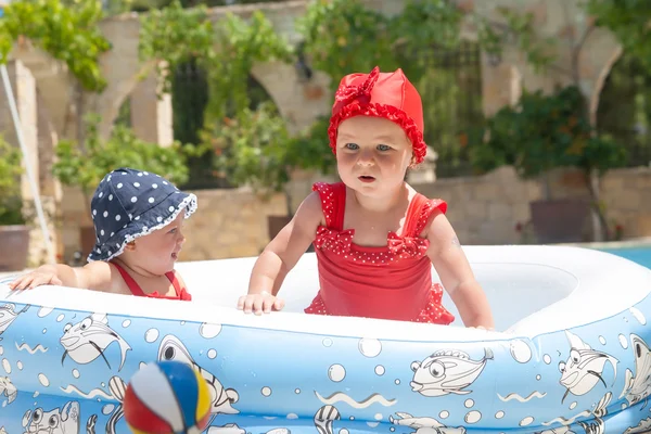 Un niño pequeño y feliz está jugando afuera en una piscina para bebés. — Foto de Stock