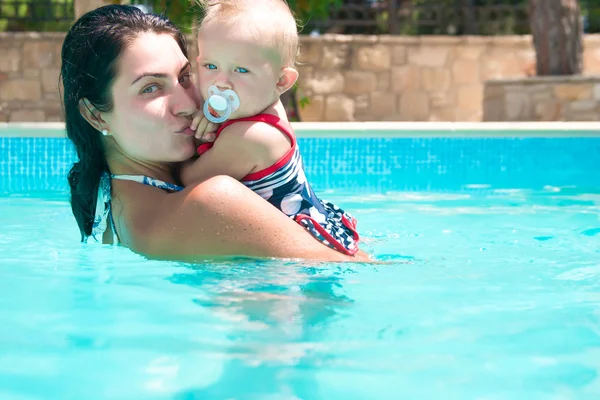 Feliz joven madre activa y bebé rizado divirtiéndose en una piscina — Foto de Stock