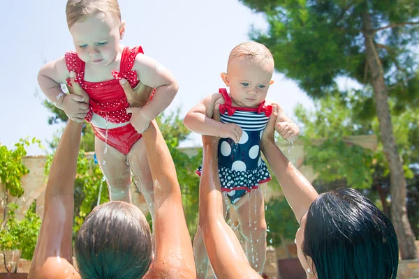 Dos niños felices con madres jugando en la piscina — Foto de Stock