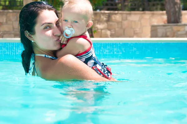Feliz joven madre activa y bebé rizado divirtiéndose en una piscina Imágenes de stock libres de derechos