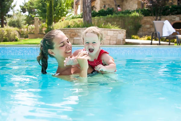 Feliz joven madre activa y bebé rizado divirtiéndose en una piscina Fotos de stock