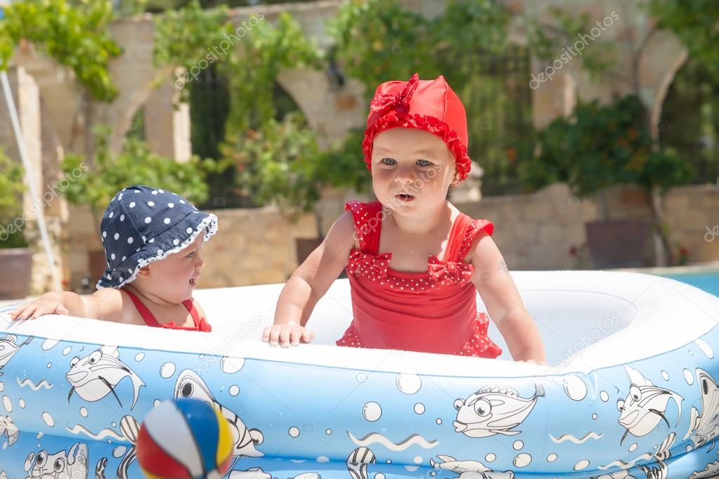 A happy young children is playing outside in a baby swimming pool
