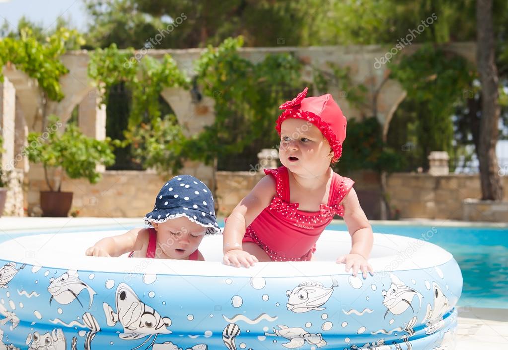 A happy young children is playing outside in a baby swimming pool