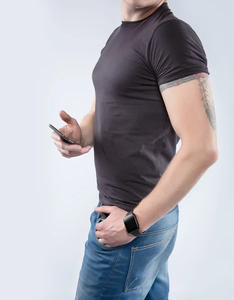 Fashion athletic young man with tattoos wearing a-shirt using a smart phone — Stock Photo, Image