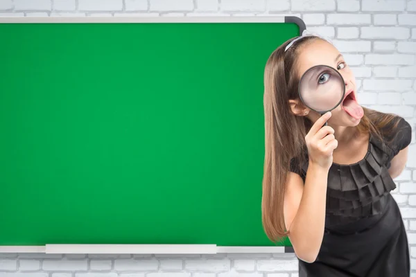 Jolie petite fille regardant à travers une loupe sur le fond du bureau de l'école. Concept éducatif — Photo