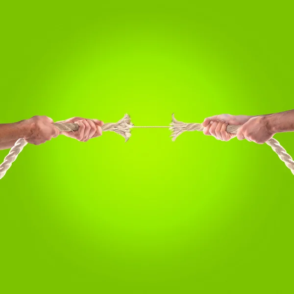 Руки людей тянут веревку на зеленом фоне. Концепция сотрудничества — стоковое фото