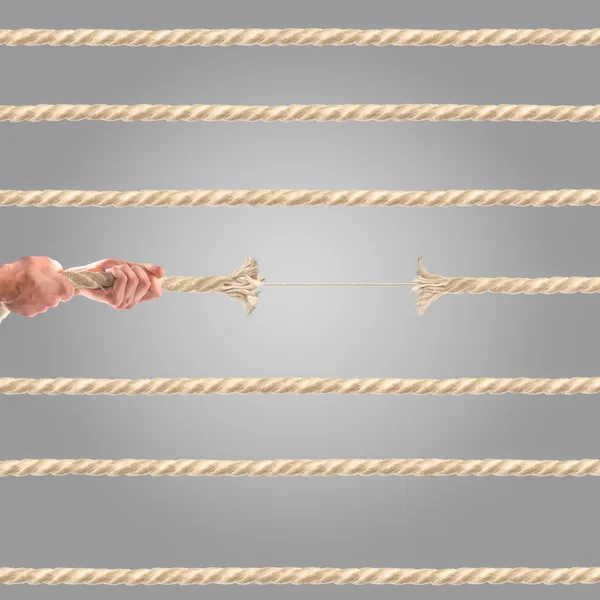 Руки людей тянут верёвку на сером фоне. Концепция конкурса — стоковое фото
