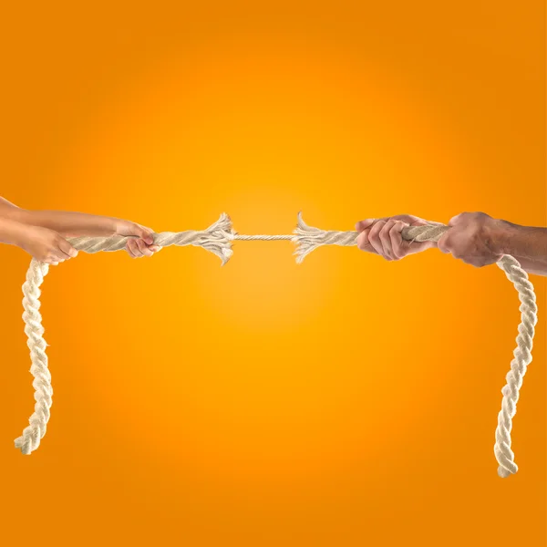Mains de personnes tirant la corde sur fond orange. Concept de concurrence — Photo
