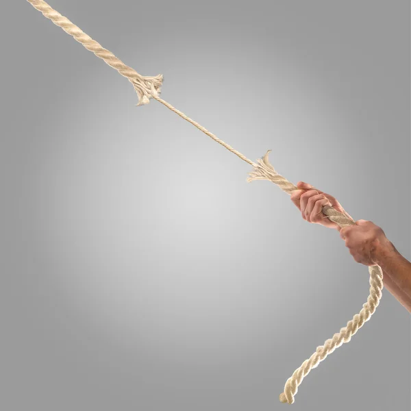 Mãos de pessoas puxando a corda em um fundo cinza. Conceito de concorrência — Fotografia de Stock