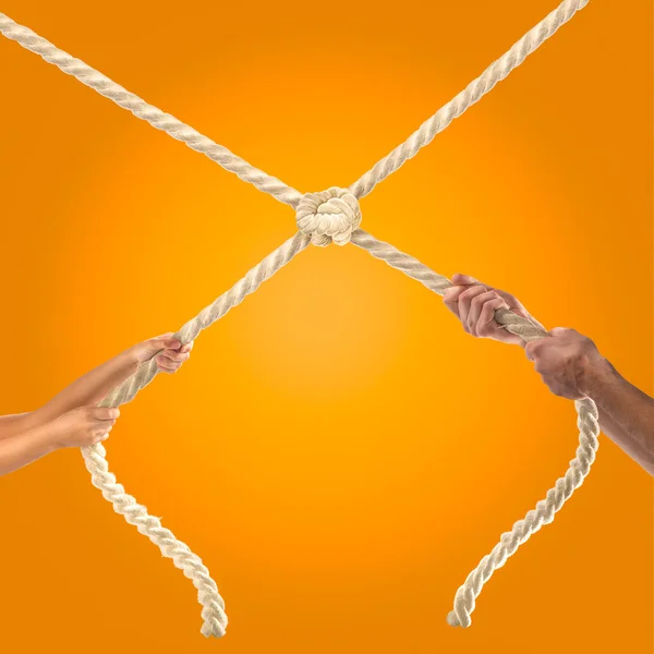 Mãos de pessoas puxando a corda no fundo laranja. Conceito de concorrência — Fotografia de Stock