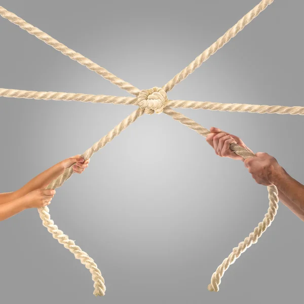 Hands of people pulling the rope on a gray background.  Competition concept — Stock Photo, Image