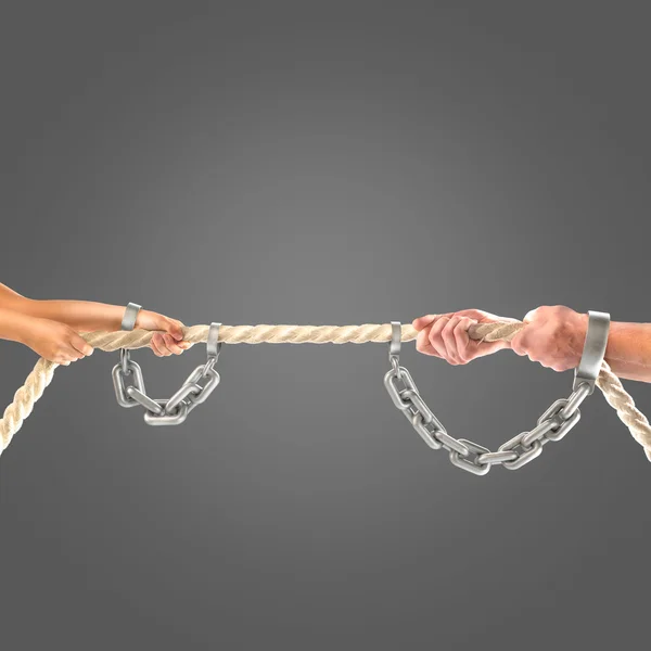 Hands girls and adult men pulling the rope in chains on black background. Competition concept — Stock Photo, Image