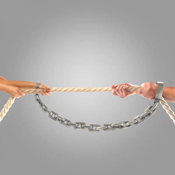 Hands girls and adult men pulling the rope in chains on a gray background.  Competition concept — Stock Photo, Image