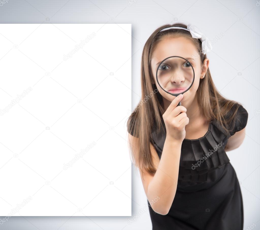 Cute  little girl looking through a magnifying glass. Educational concept