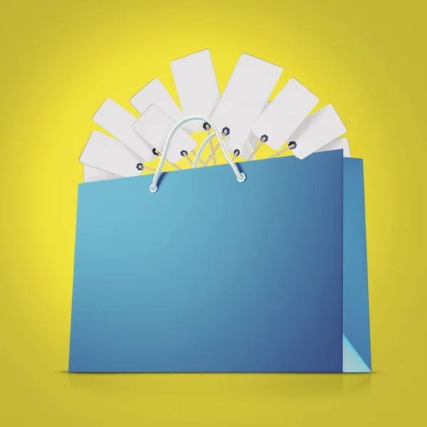 Saco de compras de papel forte azul com muitas tags no fundo amarelo — Fotografia de Stock