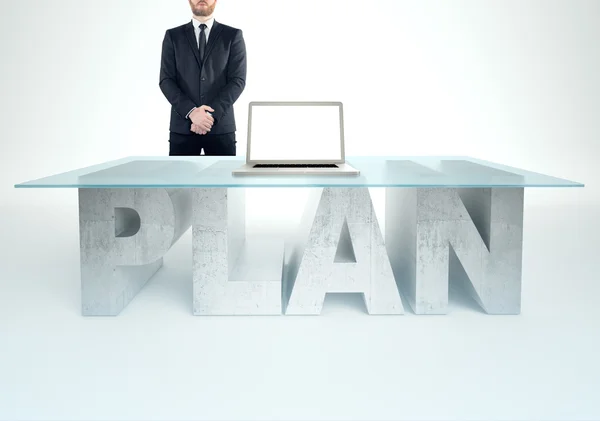 Un hombre de negocios seguro parado cerca de una mesa de PLAN. Concepto de empresas — Foto de Stock