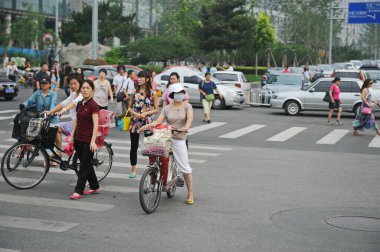 Pekin / Çin - 08.06.2012: Şehrin sakinleri ana caddeler boyunca bisiklet ve motosikletle hareket ediyorlar.