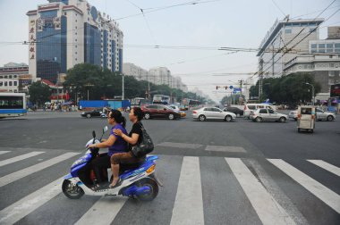 Pekin / Çin - 08.06.2012: İki kişi bir motosikletle ana caddelerde ilerliyor
