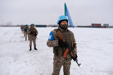 Almaty / Kazakistan - 11.20.2020: Ellerinde silah olan bir müfreze asker birbirinin arkasında duruyor. Karlı havada barış gücü tatbikatları..