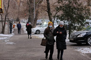 Almaty / Kazakistan - 11.20.2020: Karlı havada maskeli insanlar kaldırımda yürüyor