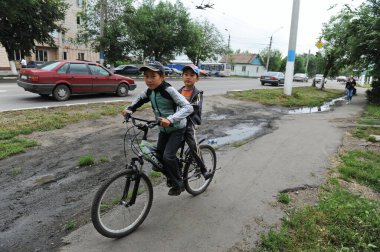 Petropavlovsk, Kazakistan - 08.08.2013: İki genç ana cadde boyunca aynı bisiklete biniyor.