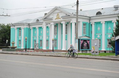 Petropavlovsk, Kazakistan - 08.08.2013: Mukanov Tiyatrosu 'nun önünden geçen bir adam bisiklete biniyor