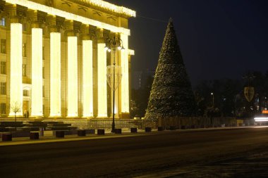Almaty, Kazakistan - 12.22.2020: Merkez Meydanı 'ndaki dekore edilmiş bir Noel ağacının arka planındaki araba farlarının çizgileri.