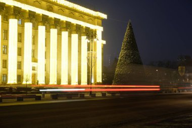 Almaty, Kazakistan - 12.22.2020: Merkez Meydanı 'ndaki dekore edilmiş bir Noel ağacının arka planındaki araba farlarının çizgileri.