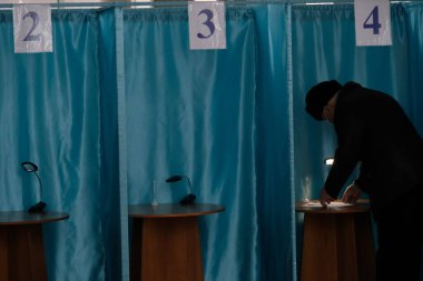 Almaty, Kazakistan - 01.10.2021: Vatandaşlar oy pusulalarını oy kabininde dolduruyorlar. Kazakistan 'da parlamento seçimleri