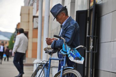 Ridder, Kazakistan - 06.05.2013: Takım elbiseli ve şapkalı bir adam bisikletinin yanında duruyor.