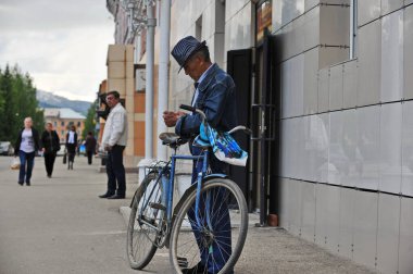 Ridder, Kazakistan - 06.05.2013: Takım elbiseli ve şapkalı bir adam bisikletinin yanında duruyor.