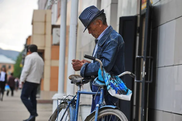 Ridder, Kazakistan - 06.05.2013: Takım elbiseli ve şapkalı bir adam bisikletinin yanında duruyor.